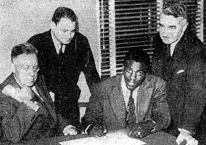 Robinson signing contract with the Montreal Royals in 1945 as Royals President Hector Racine, Branch Rickey Jr. and Royals Vice-President Romeo Gauvreau look on.