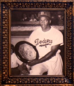 Robinson in a Dodgers uniform posing with an award circa 1948. The City Reliquary Museum