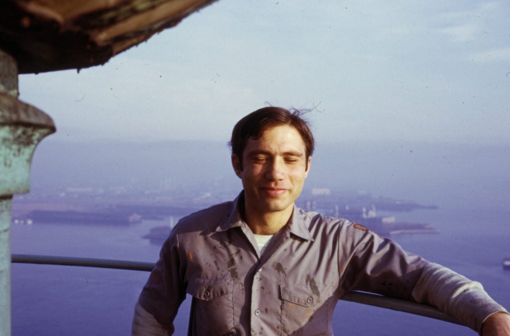 A young man blinks during a photo standing on the rim around the torch of the Statue of Liberty