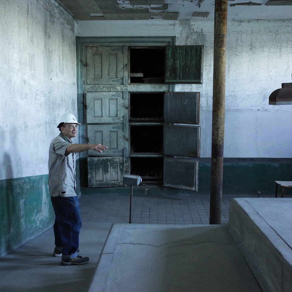 Man in hard hat points in a dusty room