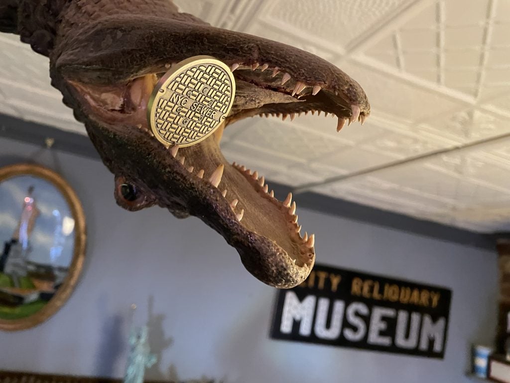 Alligator with a City Reliquary challenge coin in its mouth, photo by Jacob Ford